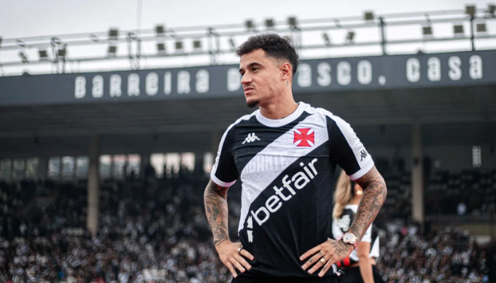 camisa titular do Vasco da Gama para a temporada 2024-2025. A camisa é predominantemente preta, com a tradicional faixa diagonal branca e detalhes em branco e vermelho. No peito, a frase "Dinamite Eterno" em jacquard homenageia o maior artilheiro da história do clube.